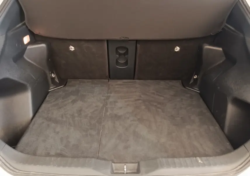 Coffre ouvert de la Toyota Yaris Cross blanc, vue intérieure montrant l’espace de chargement avec banquette arrière rabattue.