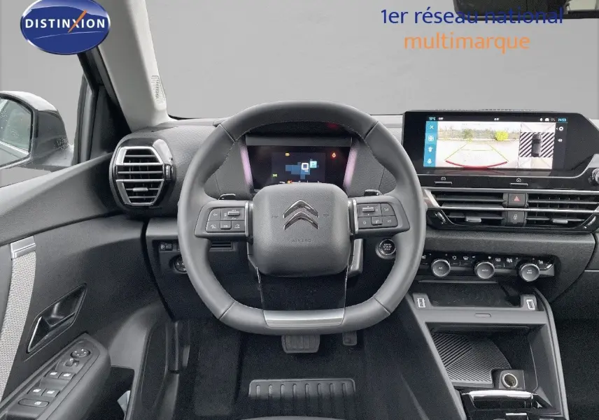 Vue intérieure du poste de conduite d'une Citroën C4 gris platinium, avec volant multifonction et écran tactile affichant la caméra de recul.