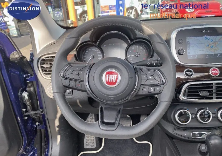 Vue intérieure centrée sur le volant du Fiat 500X bleu Venezia Metal avec tableau de bord et écran tactile visible.