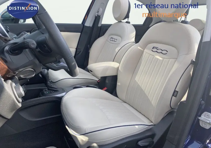 Intérieur de la Fiat 500X 2021 en cuir ivoire, vue côté gauche sur les sièges avant et le volant, ambiance lumineuse naturelle.