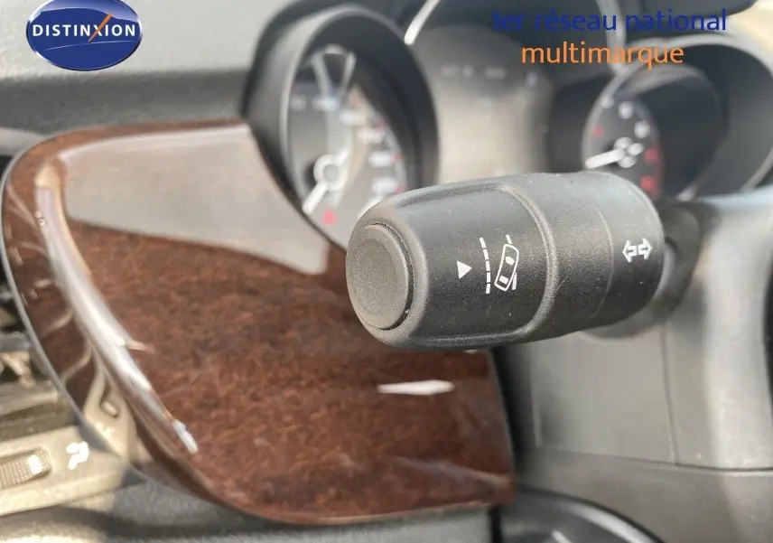 Gros plan sur la commande de régulateur de vitesse avec tableau de bord et insert bois foncé du Fiat 500X bleu Venezia Metal.