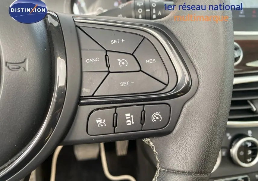 Gros plan sur les commandes de régulateur de vitesse au volant cuir d'une Fiat 500X 2021, finition Yacht Club Capri.