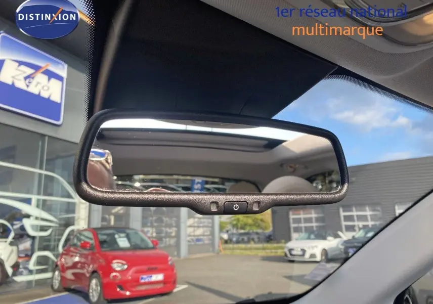 Reflet dans le rétroviseur intérieur montrant le toit ouvrant d'une Fiat 500X Bleu Venezia Metal vue de l'avant intérieur.