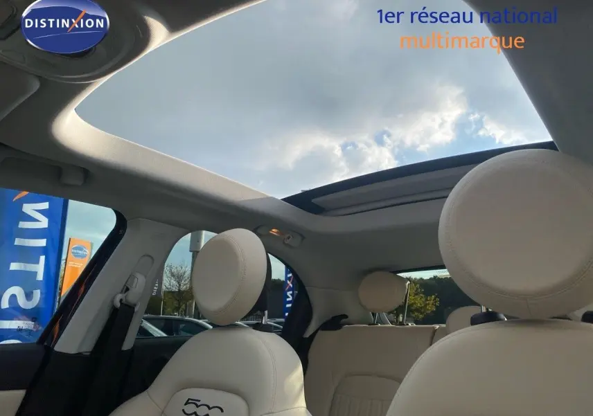 Vue intérieure du toit ouvrant panoramique et des sièges avant en cuir ivoire du Fiat 500X bleu Venezia Metal.