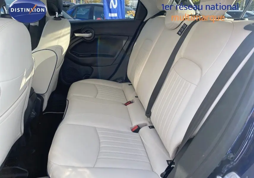 Vue côté droit de l'habitacle arrière d'une Fiat 500X 2021 avec sièges cuir ivoire et portières bleu Venezia métal.