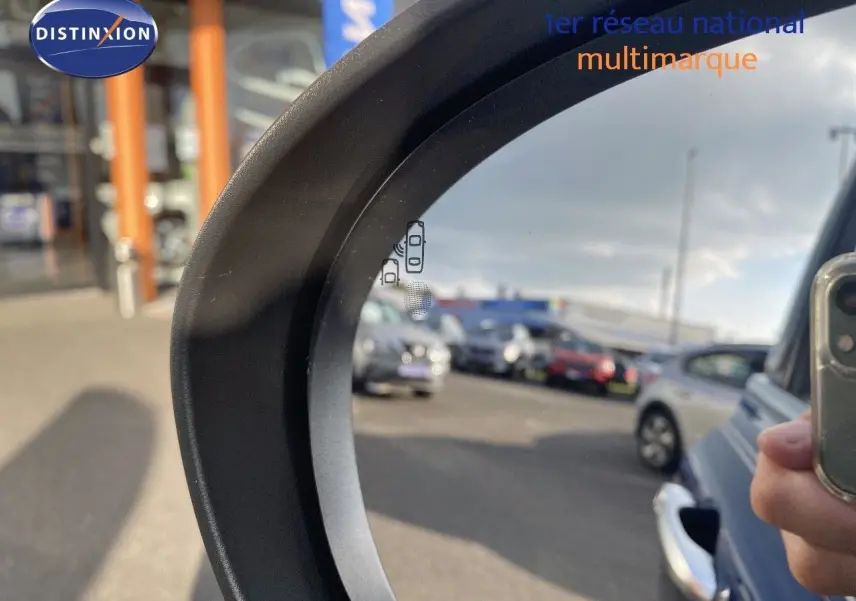 Rétroviseur côté droit montrant une FIAT 500X bleu Venezia metal en 3/4 arrière dans un parking.