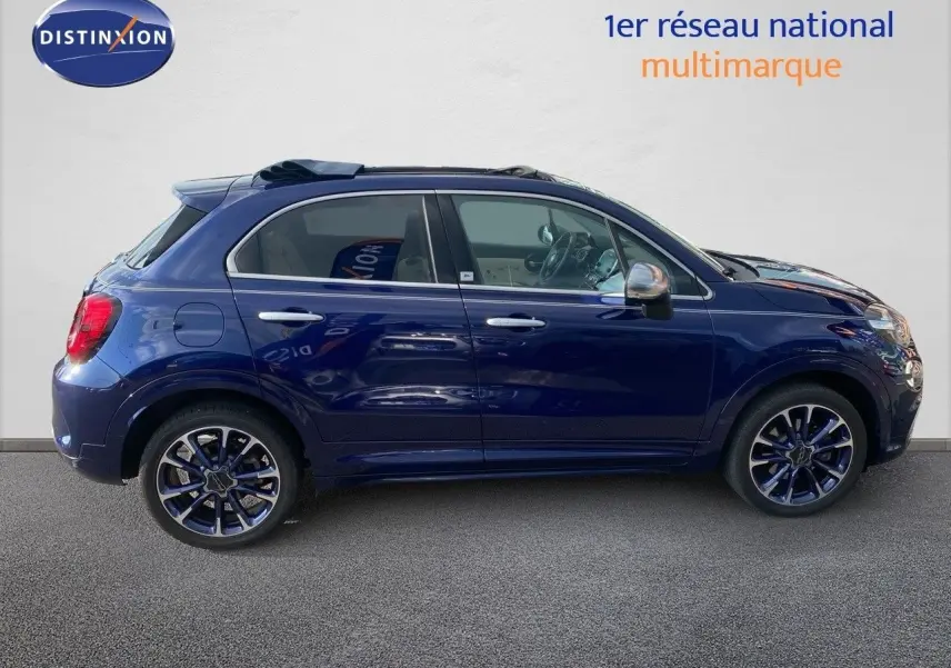 Profil côté gauche d'une Fiat 500X bleu Venezia métal avec jantes bi-ton et rétroviseurs chromés, vue en extérieur.