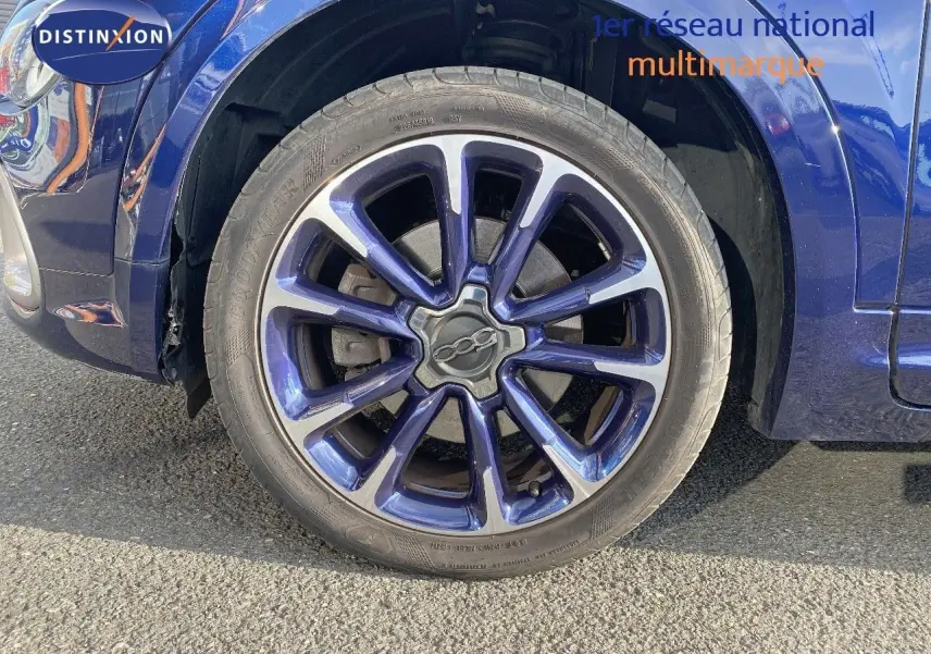 Gros plan sur la roue avant gauche d'une FIAT 500X bleu Venezia Metal avec jante alliage bicolore distinctive.