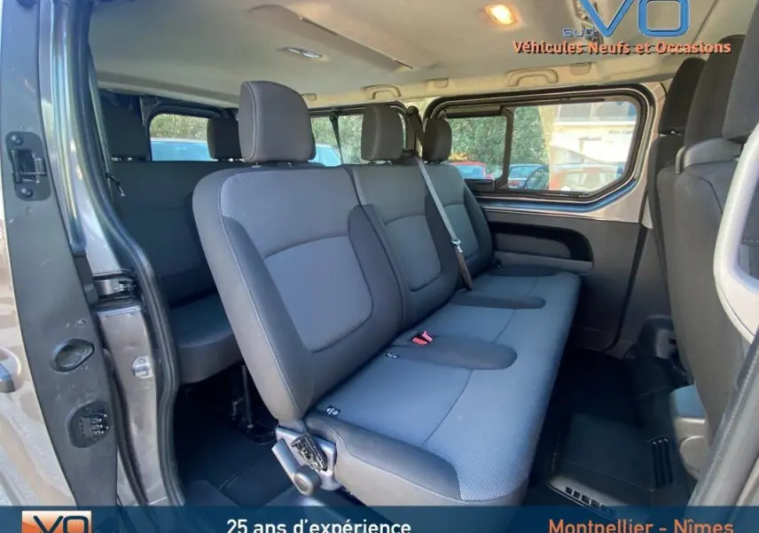 Intérieur du Renault Trafic Combi L2 gris clair, vue latérale sur la banquette arrière trois places avec porte latérale ouverte.
