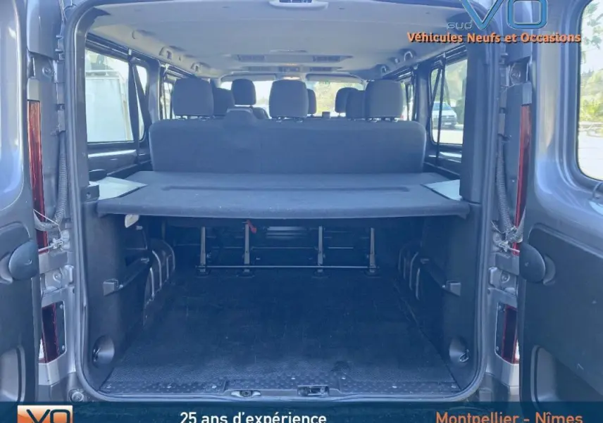 Vue arrière ouverte du Renault Trafic Combi gris clair montrant l'espace de chargement et les sièges arrière noirs.