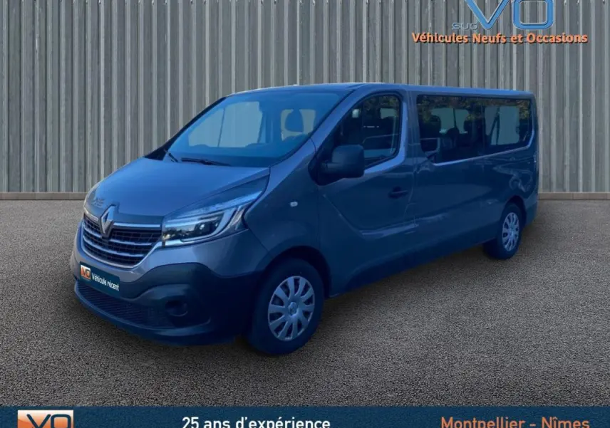 Renault Trafic Fourgon Combi gris clair vu en 3/4 avant droit avec porte latérale et vitres surteintées.
