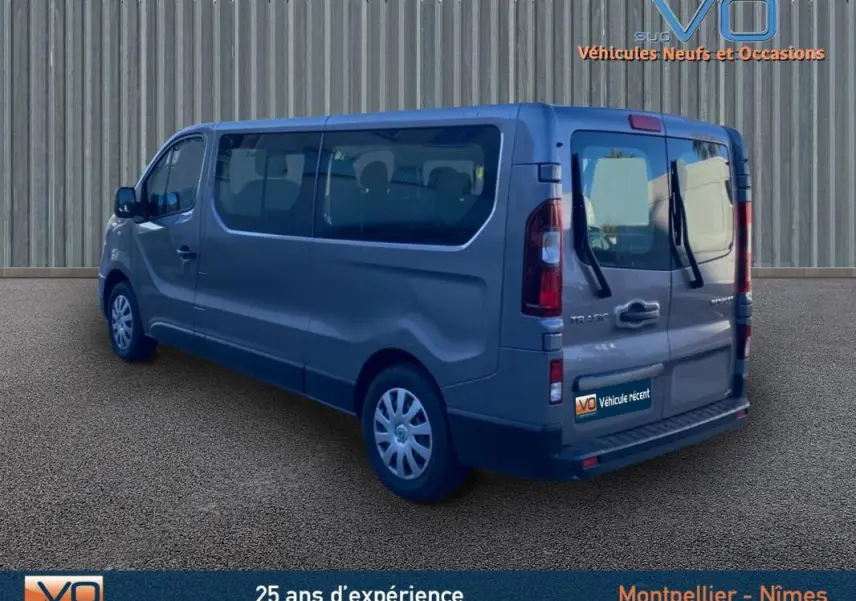 Renault Trafic Fourgon gris clair vu en 3/4 arrière droit avec vitres surteintées et porte latérale visible