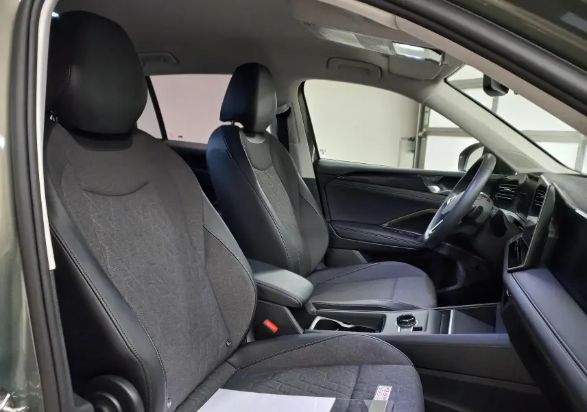 Intérieur du Volkswagen Tiguan 2025 vu côté conducteur, sièges tissu et cuir noir, tableau de bord moderne et épuré.