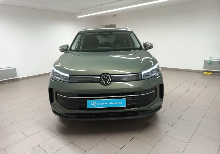 Volkswagen Tiguan 2025 Vert Cipressino vu de face avec phares allumés dans un intérieur neutre.