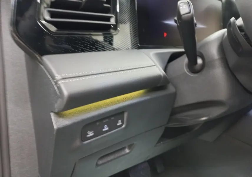 Gros plan sur la console côté gauche du Volkswagen Tiguan 2025, montrant la commande de boîte auto et les finitions en cuir noir.