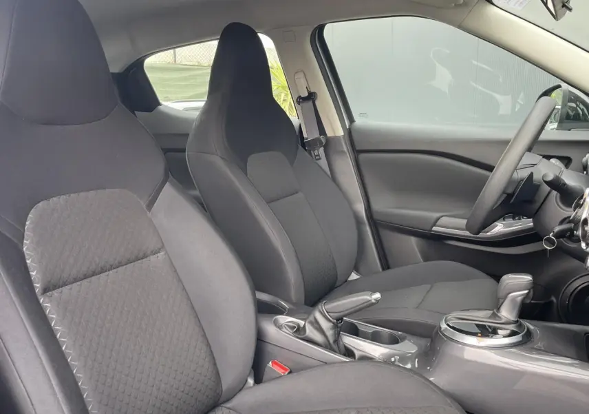 Vue intérieure côté droit des sièges avant noirs et de la console centrale du Nissan Juke 2024 gris Silver.