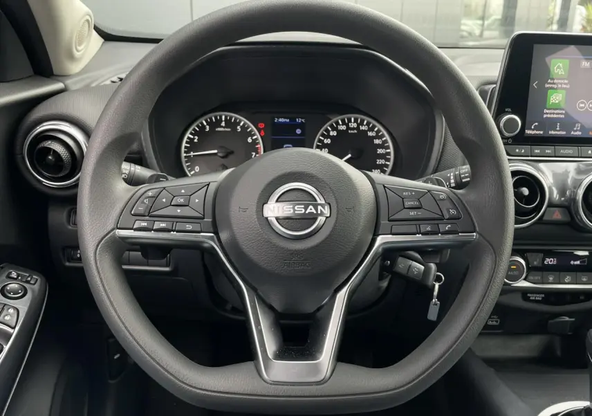 Vue rapprochée du volant multifonction noir du Nissan Juke 2024 avec tableau de bord et écran tactile visible à droite.
