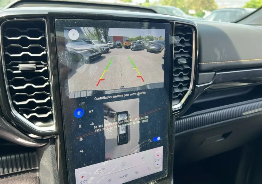 Vue intérieure du tableau de bord du Ford Ranger 2025 avec écran tactile affichant la caméra de recul et les commandes climatisation.