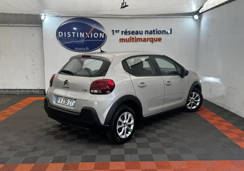 Vue 3/4 arrière droite d'une Citroën C3 beige 2021 avec feux arrière LED et jantes alliage en intérieur showroom.