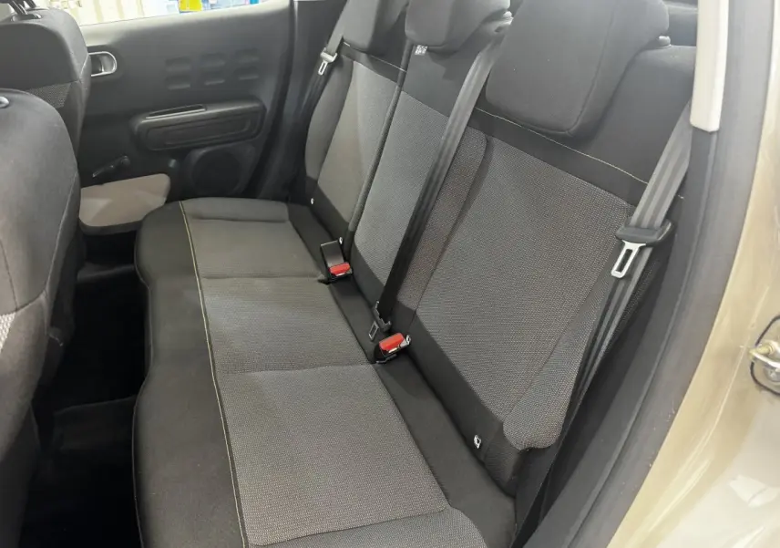 Vue intérieure côté droit sur la banquette arrière noire et grise de la Citroën C3 beige, avec ceintures de sécurité visibles.