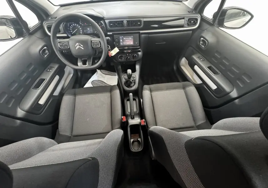 Vue intérieure avant de la Citroën C3 beige 2021, montrant tableau de bord, volant multifonctions et sièges tissu gris.