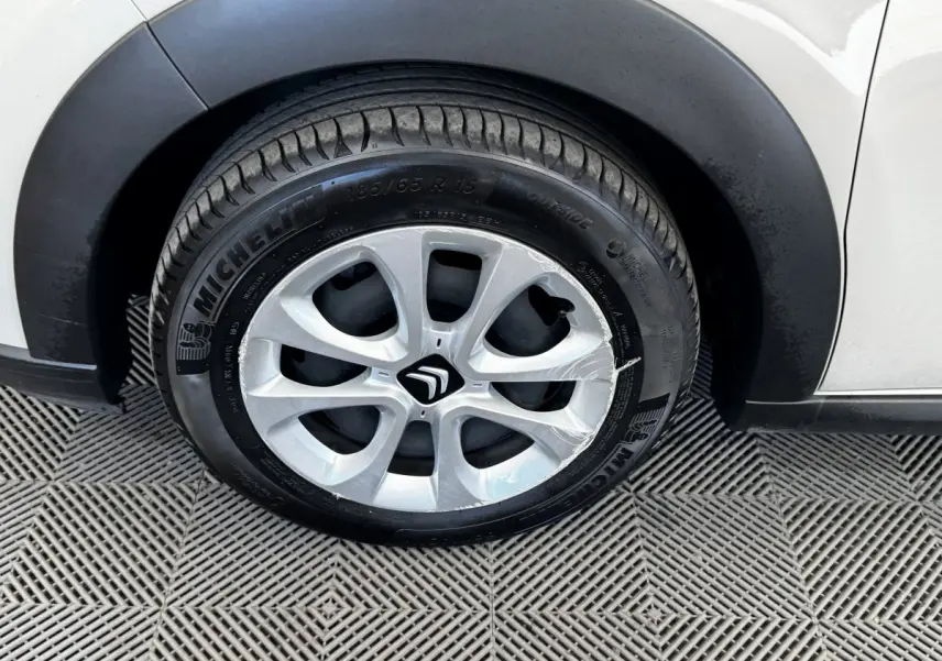 Gros plan sur la roue avant droite d'une Citroën C3 blanche avec jante alliage et pneu Michelin visible.