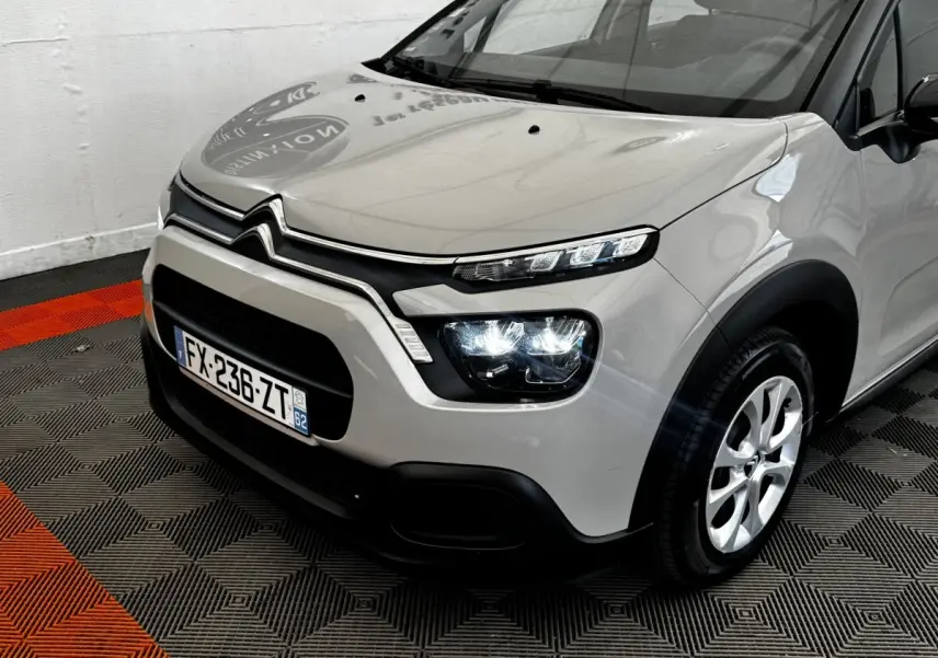 Vue 3/4 avant droit d'une Citroën C3 beige 2021 avec phares LED et calandre noire distinctive.