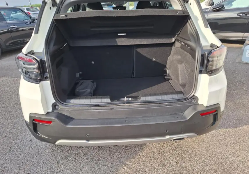 Vue arrière ouverte du coffre d'un Jeep Avenger blanc 2025, soulignant l'espace de chargement et les feux arrière LED.