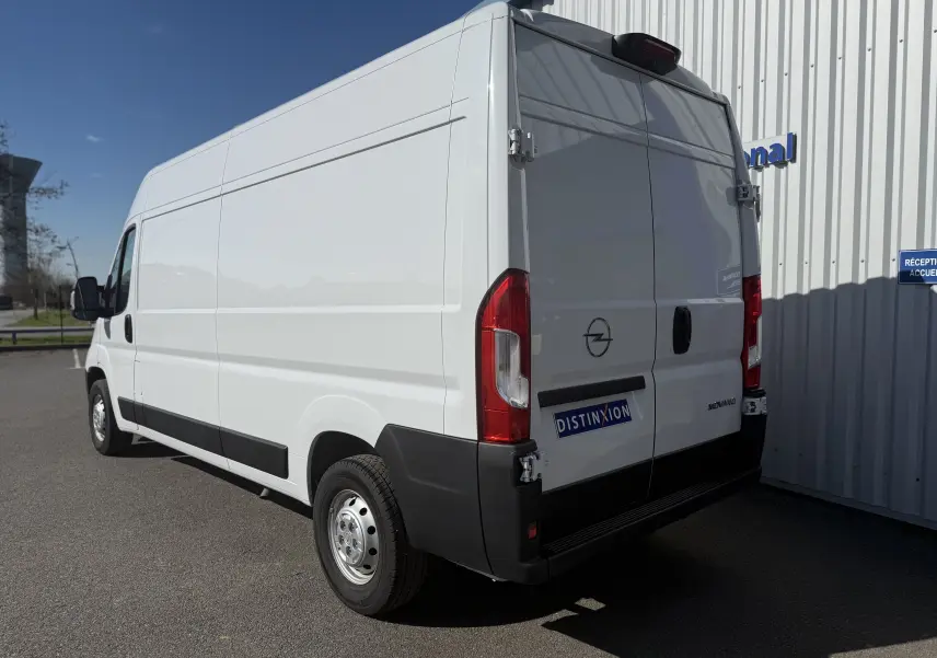 Vue 3/4 arrière droite d’un Opel Movano Fourgon blanc 2023 avec portes arrière fermées et feux rouges visibles.