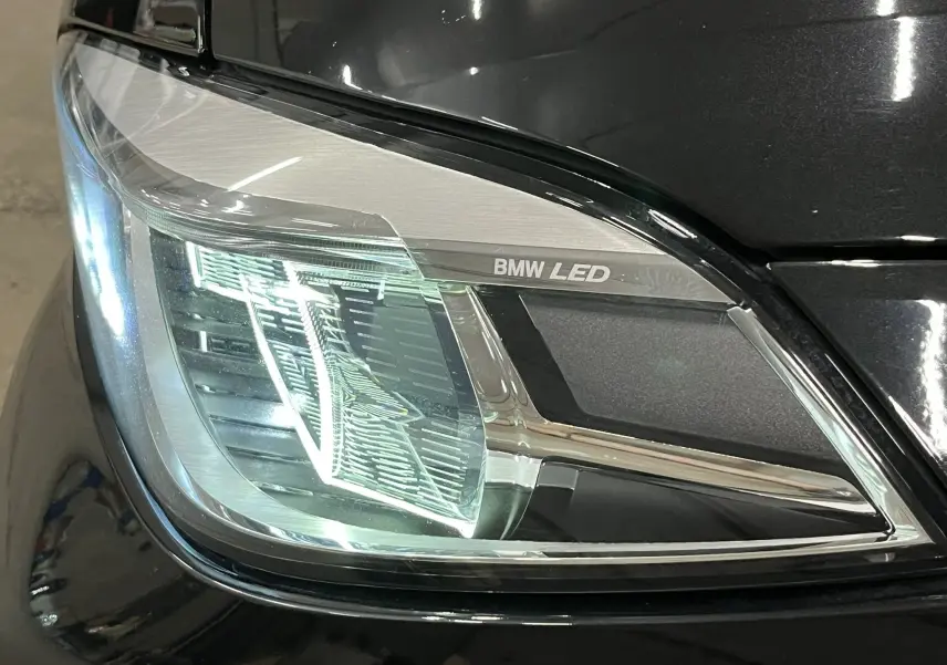 Gros plan sur le phare avant droit LED d’une BMW Série 1 F40 noir métallisé avec calandre partiellement visible.