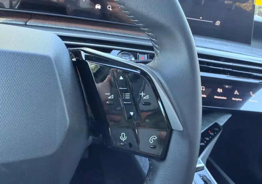 Gros plan sur les commandes au volant du Peugeot 3008 Hybrid 145 e-DCS6 Allure 2025, intérieur noir avec écran tactile.