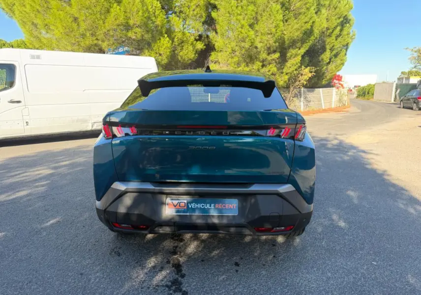 Vue arrière d’un Peugeot 3008 Hybrid 145 e-DCS6 Allure bleu 2025 avec feux arrière distinctifs en forme de griffes.
