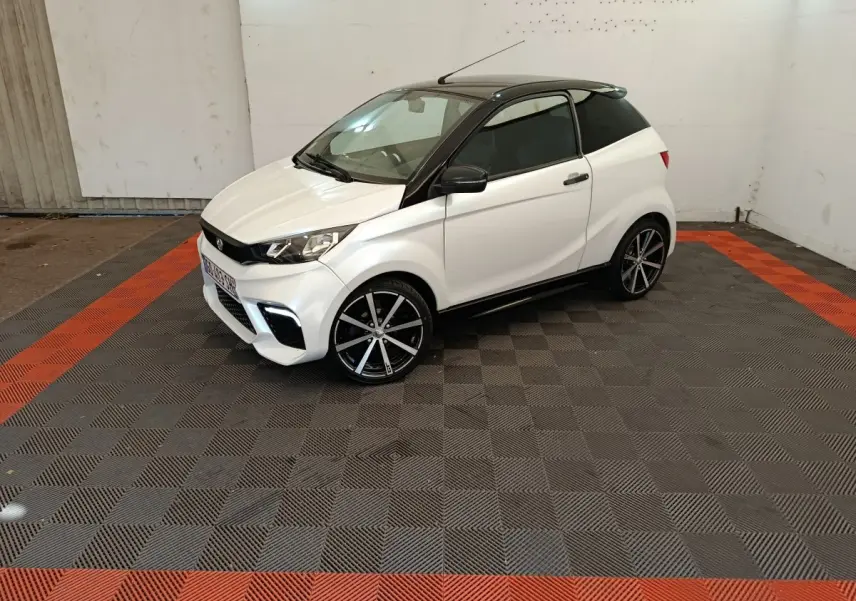 Vue 3/4 avant droite de l'AIXAM AMBITION 0.5 CITY COUPE GTI blanche avec toit noir et jantes alliage noires.