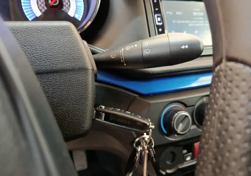Gros plan sur le volant et la clé de contact d'une Aixam Ambition 0.5 City Coupe GTI 2023, tableau de bord noir et bleu.