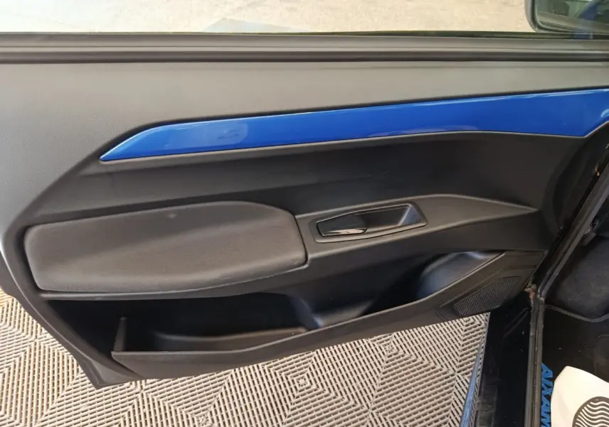Vue intérieure du panneau de porte côté conducteur de l'AIXAM Ambition 0.5 City Coupe GTI 2023 avec insert bleu et poignée noire.