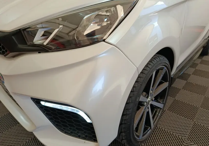 Gros plan sur l'avant droit blanc de l'AIXAM AMBITION 0.5 CITY COUPE GTI 2023, avec phare et jante noire visible.