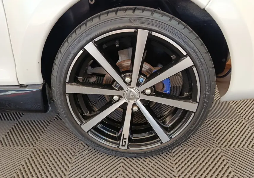 Gros plan sur la roue avant droite de l'AIXAM AMBITION 0.5 CITY COUPE GTI blanche avec jante noire et argentée, détail GTI visible.