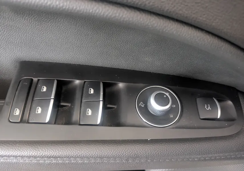 Gros plan sur les commandes de lève-vitres et réglage des rétroviseurs côté conducteur d'un Alfa Romeo Stelvio blanc 2023.