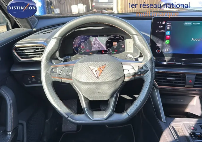 Vue intérieure centrée sur le volant en cuir noir perforé du CUPRA Formentor 1.4 E-HYBRID 2023 avec tableau de bord numérique.