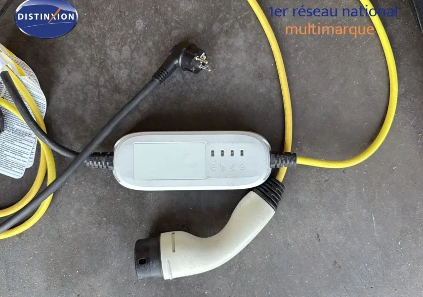 Câble de recharge hybride avec prise blanche et câble jaune sur sol gris, accessoire du CUPRA Formentor noir minuit.