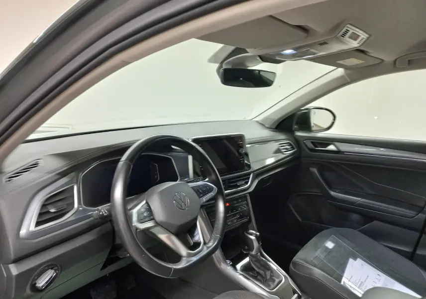 Intérieur du Volkswagen T-Roc 2023 côté conducteur, volant cuir, tableau de bord moderne et écran tactile central.