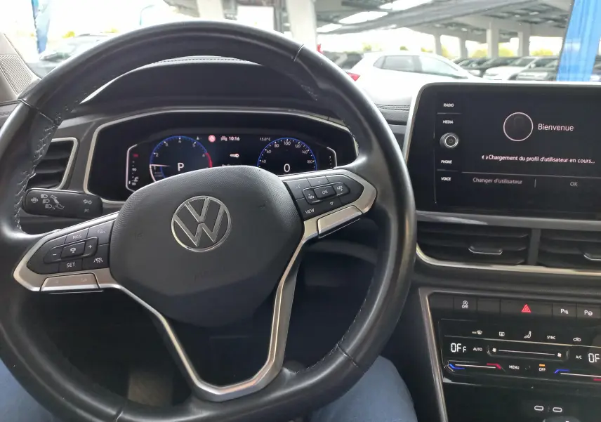 Vue intérieure centrée sur le volant noir du Volkswagen T-Roc 2023 avec tableau de bord digital et écran tactile.