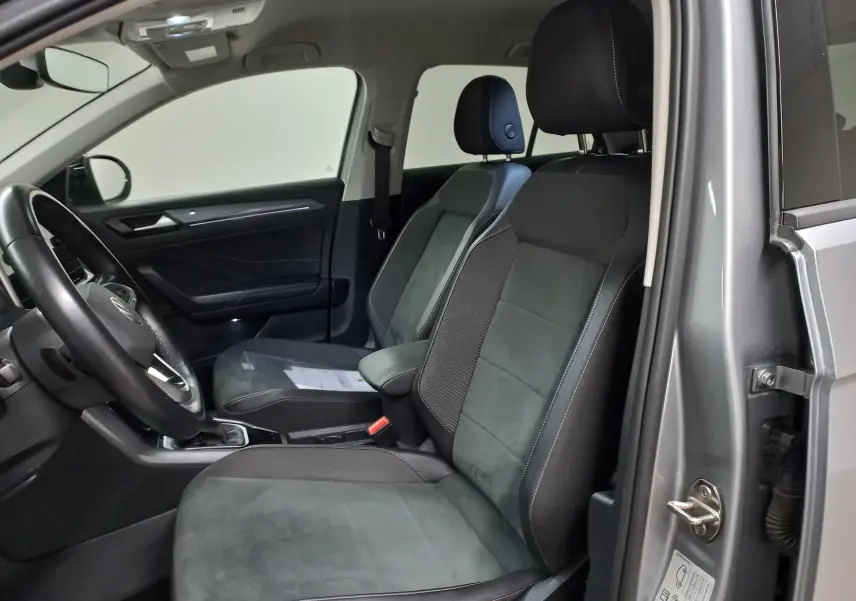 Vue intérieure côté conducteur du Volkswagen T-Roc gris pyrite, sièges tissu et alcantara noirs avec coutures contrastées.