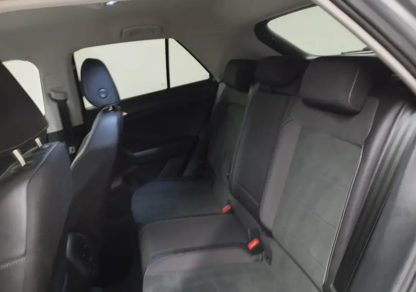 Vue intérieure des sièges arrière en tissu et cuir noir du Volkswagen T-Roc 1.5 TSI 2023 avec vitres arrière surteintées.