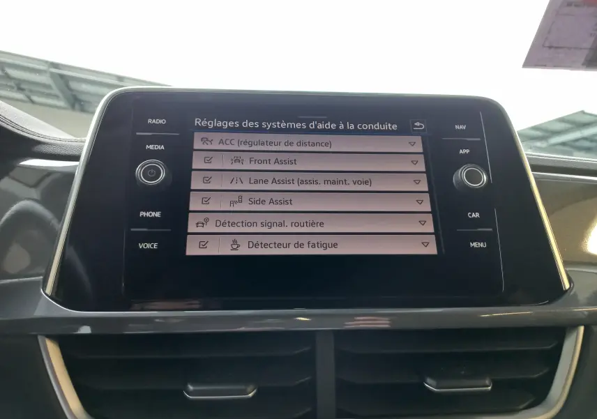 Écran central tactile du Volkswagen T-Roc 2023 affichant les réglages des aides à la conduite dans l'habitacle.