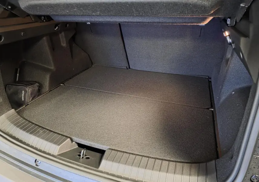 Coffre ouvert du Dacia Duster 1.6 Hybrid noir, montrant un espace de chargement plat et bien éclairé.