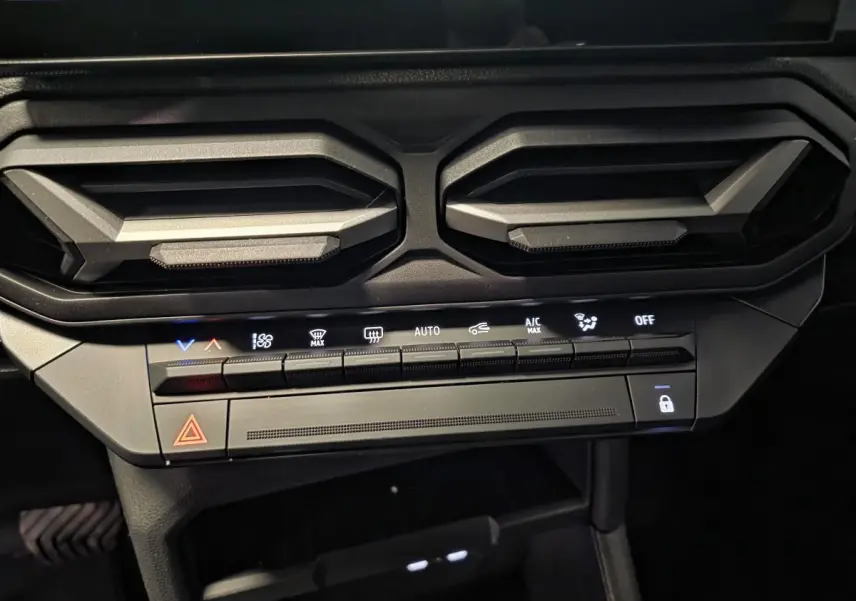 Détail des aérateurs gris acier et des commandes de climatisation du tableau de bord du Dacia Duster noir 2025.