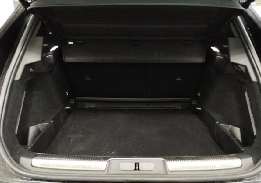 Coffre ouvert vu de l'arrière d'un DS7 noir Perla, montrant un espace de chargement spacieux et propre.