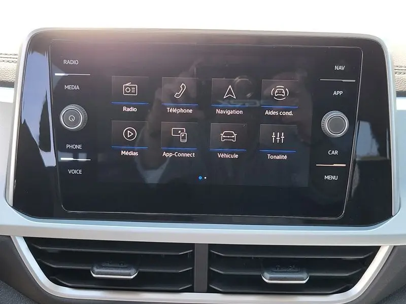 Écran tactile central du Volkswagen T-Roc 2025 affichant les options radio, téléphone, navigation et aides à la conduite.
