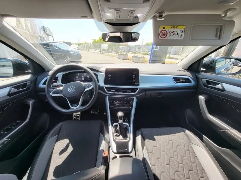 Vue intérieure avant du Volkswagen T-Roc 2025, tableau de bord moderne avec écran tactile central et volant multifonction.